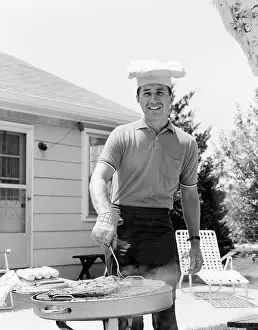 Grilling: 1960s SMILING MAN OUTDOORS IN BACKYARD PATIO
