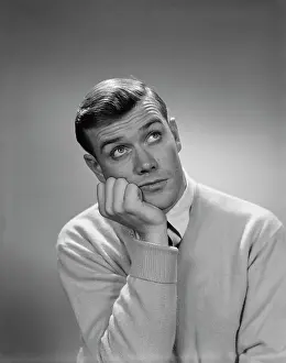 Quizzical: 1960s YOUNG MAN HAND TO CHEEK LOOKING UP QUIZZICAL