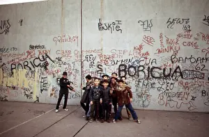 Latina: 1970s America. Young boys pose in front of a graffitied