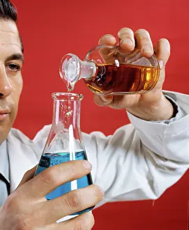 Progressing: 1970s Lab Worker Man Pouring Liquid From Bottle Into Flask