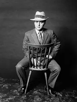 Slick: 1970s - Man Seated Backwards on Chair Looking at Camera