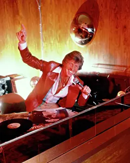 Discotheque: 1970s Smiling Man Disk Jockey Speaking into Microphone at