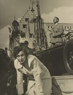 Right Wing: Adolf Hitler standing in an open automobile, with