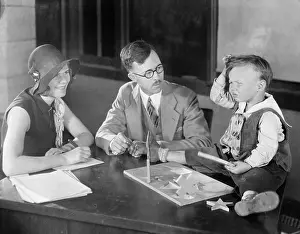 Educate: Adults testing little boy doing puzzle