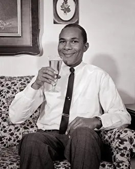 Consume: African-American Man Smiling Sitting on Couch Drinking