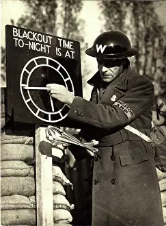 Adjusts: An Air Raid Warden adjusts the Blackout Time indicator