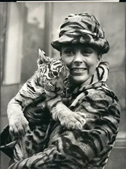 Topcoat: Air stewardess in tigerskin coat and hat, with tiger cub