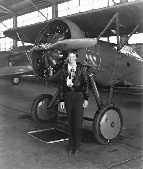 Tntarlcgr: Amelia Earhart standing next to an airplane, July