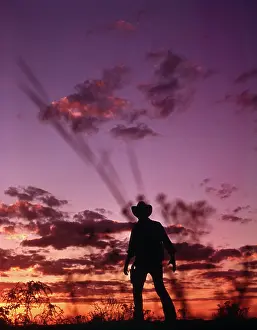 Gunslinger: Anonymous Cowboy Gunfighter Silhouetted at Dusk by Sunset