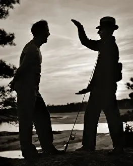 Exaggeration: Anonymous Silhouette of Two Men one Wearing Hat