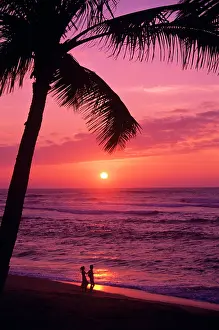 Surfer: Anonymous Silhouetted Couple walking Along Tropical