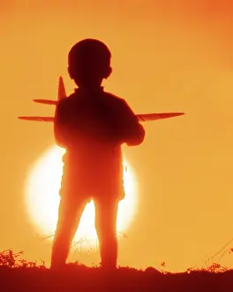 Dreamlike: Anonymous Silhouetted Small Boy Holding Model Airplane