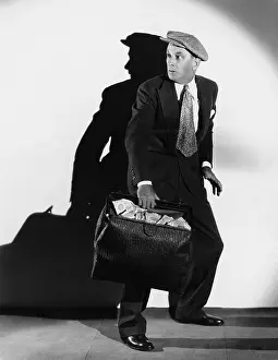 Cautious: Anxious man with bag of cash