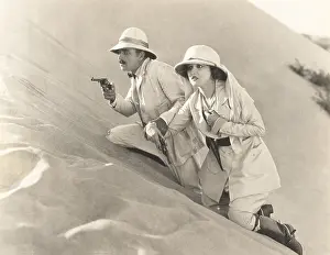 Handguns: Armed couple climbing up sand dune