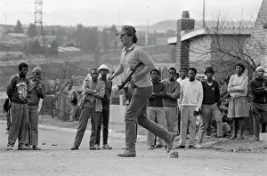 Inkatha: An armed policeman runs past local spectators