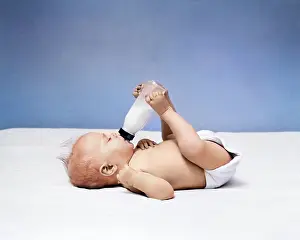 Diaper: Baby Lying on Back Drinking From Milk Bottle Held