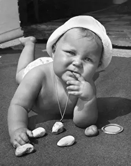Thoughtful: Baby playing with pebbles