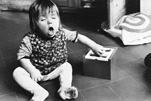 Sneeze: A baby sits on the floor with a toy