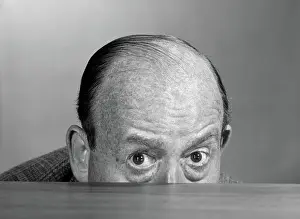 Desktop: Balding man peeking over desktop with only top