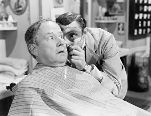 Seriousness: Barber looking at a man's face through a magnifying glass