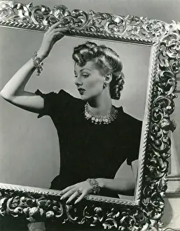 Tops: Blonde 1940s model in black top behind picture frame