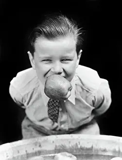 Bobbing: Boy Bobbing For Apples with An Apple in his Mouth Looking