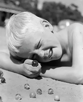 Squint: BOY CROUCHING SHOOTING MARBLES CONCENTRATION