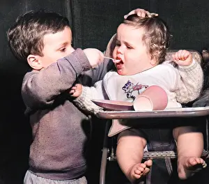Highchair: Boy feeding baby in a high chair