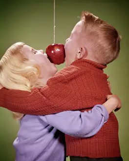 Bobbing: Boy and Girl Hugging While Trying to Bite Apple