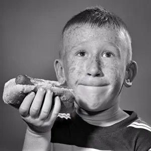 Consume: Boy Holding a Hot Dog with a Bite Taken Out of It