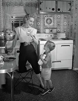 Pushers: Boy in kitchen holding bottle of milk looking