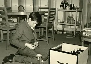Soda: Boy kneeling on the floor sorting out some glass jars