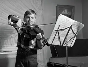 Scowl: Boy in living room practicing violin with determined