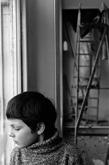 Thoughtfully: Boy looking thoughtfully downwards through a window