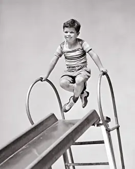 Slippery: Boy at Top of Playground Slide Pushing Up on Hand