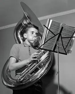 Tubas: Boy playing the tuba while reading from sheet