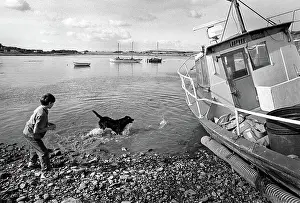 Galloway: A boy plays with a black dog in the harbour at Garlieston