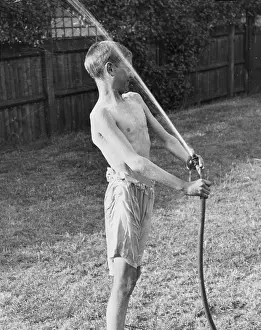 Shirtless: Boy plays with water hose 1933
