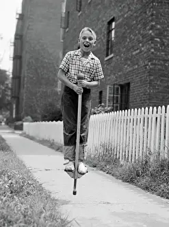 Bounce: Boy on pogo stick on sidewalk