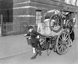 Lcgr1406: A boy pulls, as his mother pushes, a cart loaded