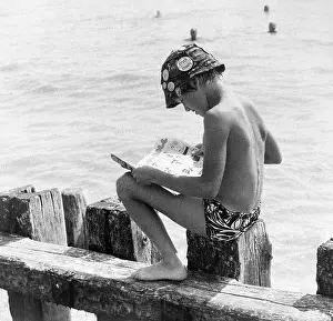 Breakwater: Boy sitting on breakwater reading a comic
