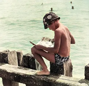 Breakwater: Boy sitting on breakwater reading a comic