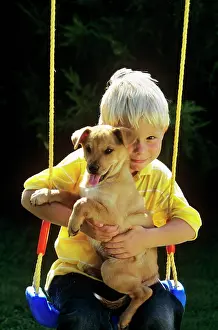 Tay001: Boy sitting with puppy on swing looking at camera