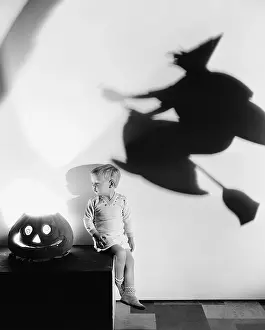 Enigma: Boy sitting on a table with a pumpkin and a shadow