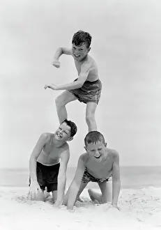 Playmates: Three boys in bathing suits form a pyramid in