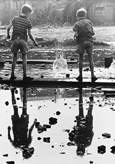 Plank: Two boys drop bricks into a puddle