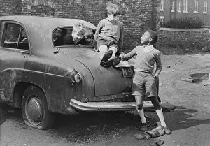 Tyre: Three boys playing on an abandoned car