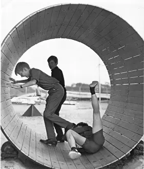 Three boys playing inside a large barrel