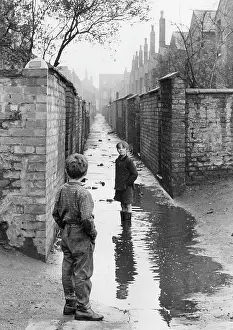 Slum: Two boys playing in a large puddle - Manchester, 1966