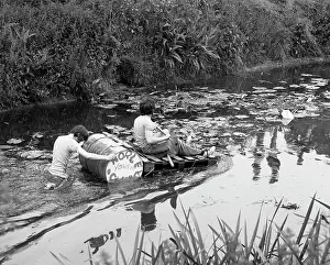 Tony Boxallfrps: Two boys with a raft make their way along a river